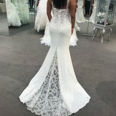 the back of a woman's white wedding dress in front of a mirror at a bridal shop