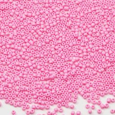 pink beads are scattered on a white surface