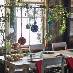 a dining room table with christmas decorations hanging from it's branches and pine cones