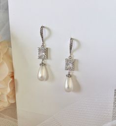 Elegant. Classic. Perfect. Featuring 15mm teardrop shell pearls (natural), this elegant pair of earrings will add glamour to any wedding dress or formal ensemble. All it takes is a simple glance at this unique design to see its extremely classy look that makes an elegant and feminine statement. Shining brightly and quite eye-catching, the shimmer of the pearls is given an extra boost by the clear cubic zirconia that adorn them. Length: 2" (approx. 5cm); Width: 0.4" (approx. 1cm); Weight: 6g. Ava White Pearl Drop Clip-on Earrings For Wedding, Elegant White Clip-on Earrings, Classic Teardrop Earrings For Party, Elegant Pear-shaped Pearl Earrings For Anniversary, Pearl Drop Dangle Clip-on Earrings For Wedding, Teardrop Pearl Pendant Earrings For Formal, Classic Pearl Teardrop Earrings, Elegant Pearl Drop Clip-on Earrings For Anniversary, White Elegant Teardrop Dangle Earrings