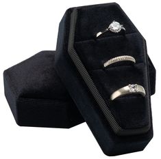 two wedding rings are in a velvet ring box, with one diamond set on top