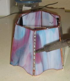 a stained glass lamp shade with a knife sticking out of the bottom and inside it