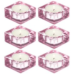 six pink glass candle holders with white candles in them