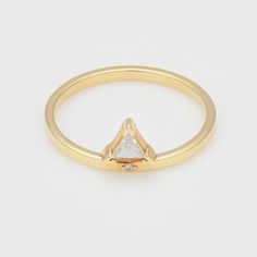 a gold ring with a white diamond in the middle and a small triangle on top