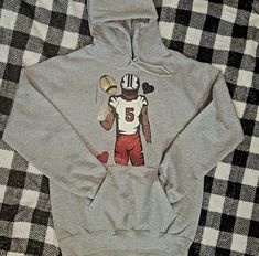 a hoodie with a football player on it is laying on a plaid bed sheet