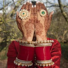 a woman with her hands covering her face and arms covered by henna tattoos,