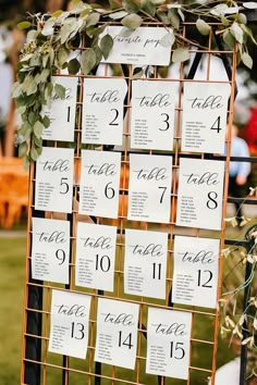 the seating cards were placed on a metal stand with greenery