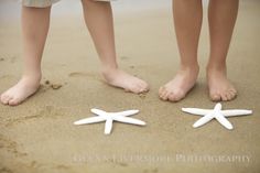 two people standing next to each other in the sand with starfish on their feet