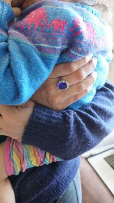 a woman holding a baby in her arms with a ring on it's finger