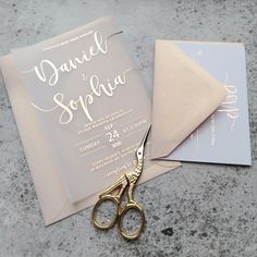 a pair of gold scissors sitting on top of a table next to a wedding card