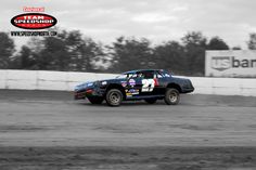 a black and white photo of a dirt track with a car in the middle of it