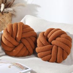 two brown knotted cushions sitting on top of a bed