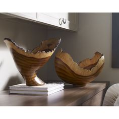 two wooden bowls sitting on top of a table next to a white book and chair