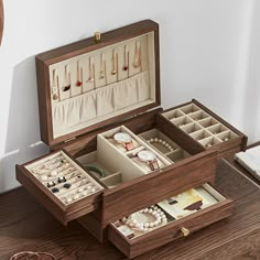 an open wooden jewelry box on top of a table next to a clock and other items