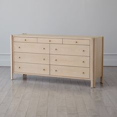 a wooden dresser sitting on top of a hard wood floor next to a white wall