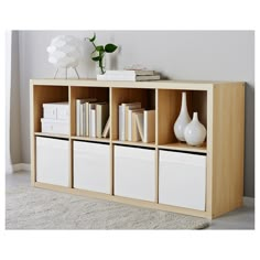 a book shelf with books and vases on it next to a white rug in a room