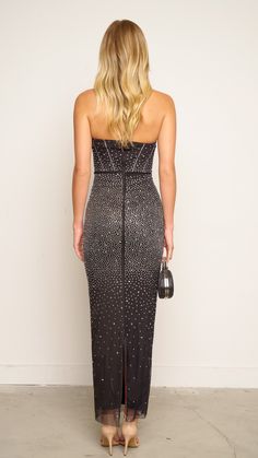 the back of a woman wearing a black dress with silver sequins on it