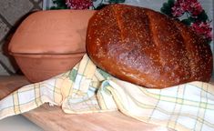 a loaf of bread sitting on top of a cutting board next to a potted plant