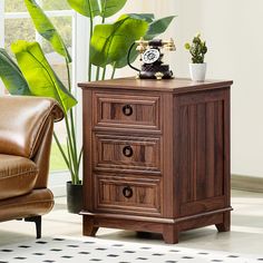 a brown leather chair sitting next to a wooden cabinet with two drawers and a telephone on top