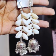 Embrace your love for nature and unique craftsmanship with our Bohemian Cowrie Shell Earrings. Each earring features carefully selected white cowrie shells arranged in a beautiful cascading pattern, culminating in an ornate oxidized silver bell that adds an elegant jingle with every movement. These earrings are a perfect blend of natural beauty and artisanal charm, ideal for enhancing any outfit with a touch of boho-chic elegance. Materials Used: Cowrie Shells: Naturally harvested white cowrie s Bohemian Bridal Earrings With Latkans In Silver, Bohemian Silver Bridal Earrings With Latkans, Bohemian Bridal Silver Earrings With Latkans, Bohemian Latkans Earrings For Beach, Traditional Metal Jewelry For Beach, Traditional Nickel-free Earrings For Beach, Bohemian Sterling Silver Jewelry With Latkans, Traditional Silver Beaded Earrings For Pierced Ears, Bohemian Sterling Silver Danglers For Festive Occasion