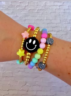 a woman's arm with two bracelets and a smiley face charm on it