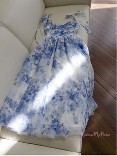 Regal and refined, this blue floral homecoming dress is a stunning choice for any special occasion. The dress is adorned with a delicate blue floral print that is both classic and contemporary, creating a look that is as elegant as it is fresh. The bodice features ruched detailing that enhances the bust and adds texture, while the off-the-shoulder straps with charming bow accents provide a feminine and romantic touch. The waist is cinched with a slender tie, allowing the full skirt to drape beau Blue Floral Sundress For Garden Party, Light Blue A-line Midi Dress With Floral Print, Light Blue Floral Dress For Summer, Spring Blue Chiffon Midi Dress, Blue Chiffon Midi Dress For Spring, Blue Floral Dress For Garden Party In Summer, Blue Floral Print Dress For Summer, Blue Chiffon Dress With Sweetheart Neckline, Blue Floral Midi-length Dress For Spring