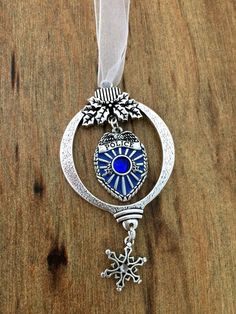 a christmas ornament hanging on a wooden table with ribbon and snowflake