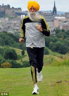 a man with a long white beard running in the grass wearing a turban