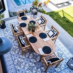 an outdoor dining table with black and white placemats next to a swimming pool