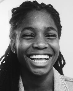 a black and white photo of a woman with dreadlocks smiling at the camera