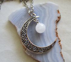 An antiqued silver filigree crescent moon combined with a natural quartz crystal ball. The quartz has natural inclusions. This comes with a 24 inch silver plated chain. Quartz crystal is the most abundant gemstone in the earth's crust. It is found on every continent. Clear quartz is considered a power stone and can enhance the metaphysical properties of other stones. Quartz Crystal has a similar vibration as humans. Using a crystal to meditate and wearing or keeping a crystal helps to a better u Silver Moon Phase Crystal Necklace, Silver Round Crystal Necklace With Moon Charm, Silver Moon-shaped Crystal Necklaces With Gemstone, Silver Moon-shaped Crystal Necklace With Gemstone, Silver Round Crystal Necklaces Mystical Style, Celestial Silver Moon Crystal Necklace, Silver Half Moon Moonstone Jewelry, Silver Moon-shaped Crystal Necklace For Gifts, Silver Crystal Necklace With Moon Charm For Gift