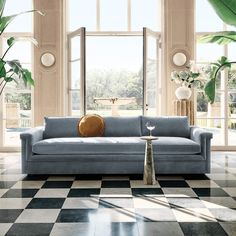 a living room with checkered flooring and blue couch in front of large windows