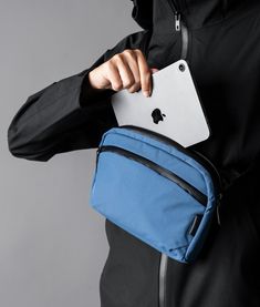 a man in black jacket holding a blue bag with an apple logo on the side