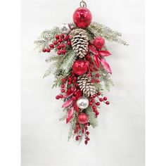 a christmas decoration hanging from the side of a wall with pine cones and red ornaments