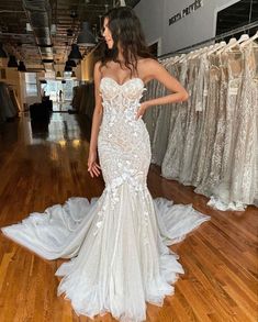 a woman standing in front of a rack of wedding dresses at a bridal shop