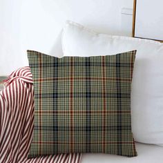 a plaid pillow with a red ribbon on the side and white pillows in the background