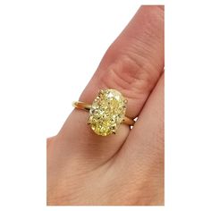 a woman's hand with a yellow diamond ring on her left finger and the center stone is in gold