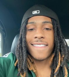 a man with dreadlocks sitting in the back seat of a car smiling at the camera