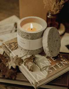 a candle sitting on top of a book next to an autumn leaf and other items