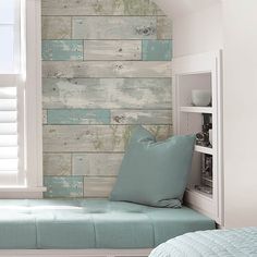 a bed sitting under a window next to a wooden wall mounted on the side of a wall