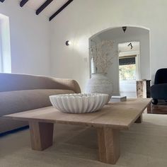 a white vase sitting on top of a wooden table in a living room next to a couch