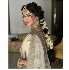 a woman in a white and gold bridal gown with her hair pulled back into a bun