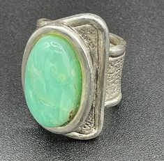 Introducing this most unusual and elegant Sterling Silver Ring with large Chrysoprase cabochon. Crafted with an eye for beautiful stones, this ring features the soothing colors of moss green and warm brown highlighted by a textured but simple sterling silver design.  The elegance and simplicity of this large ring is show stopping. The size is 10.5 so perfect for an index or middle finger. Whether you're dressing up for a special occasion or adding a touch of glamour to your everyday look, this r Modern Green Cabochon Rings, Unique Cabochon Emerald Ring, Collectible, Unique Oval Cabochon Emerald Ring, Unique Green Cabochon Opal Ring, Unique Green Cabochon Ring, Unique Chrysoprase Ring With Large Stone, Green Oval Modernist Jewelry, Green Modernist Oval Jewelry, Green Board