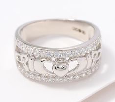 a white gold ring with two hearts on the side and diamonds in the middle, sitting on top of a piece of paper