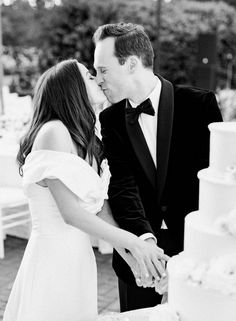 a bride and groom kissing in front of a wedding cake