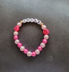 Pink Smile bracelet made with light and dark pink alternating round beads. Elastic band. Can be customized. Adjustable Pink Name Bracelet With 8mm Beads, Pink Friendship Bracelets With 8mm Round Beads, Pink Beaded Name Bracelet As A Gift, Pink Beaded Name Bracelet As Gift, Pink Beaded Name Bracelet For Gift, Casual Pink Stretch Bracelet With Round Beads, Adjustable Handmade Pink Rosary Bracelet, Casual Personalized Pink Beaded Bracelets, Casual Pink Personalized Beaded Bracelets