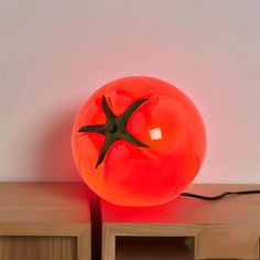 a red light sitting on top of a wooden table next to a white wall and shelf