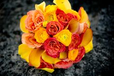 a bridal bouquet with orange and yellow flowers on the ground in front of a black background