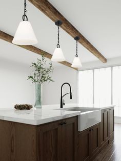 a kitchen with an island, sink and three lights hanging from it's ceiling