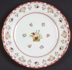 a white plate with red trim and flowers on the rim is sitting on a black surface